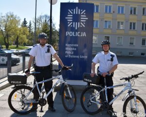 zdjęcie kolorowe, dwaj policjanci w patrolu rowerowym  stoją przy rowerach