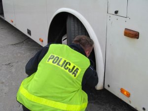 Policjant sprawdzający koło autobusu miejskiego