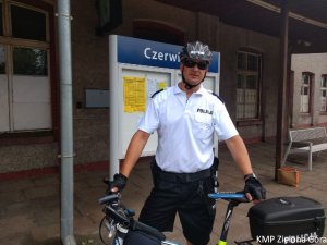 Zdjęcie policjanta stojącego przy rowerze na dworcu