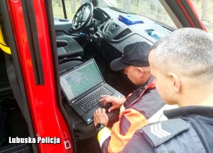 Zdjęcie policjantów sprawdzających mapę na laptopie