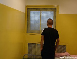 Zdjęcie mężczyzny stojącego w celi patrzącego przez kraty w oknach