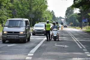 Zdjęcie policjanta sprawdzającego alkomatem trzeźwość kierowcy siedzącego na motorze