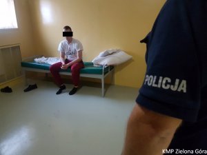 Policjant stojący przed osadzonym siedzącym na łóżku w celi