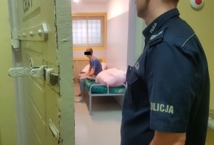 Policjant obserwuje zatrzymanego mężczyznę w celi