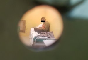 Zatrzymany mężczyzna który czyta książkę widziany przez wizjer w drzwiach celi