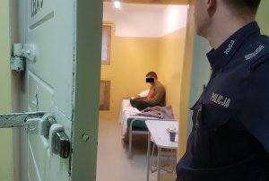 Policjant obserwuje zatrzymanego mężczyznę w celi