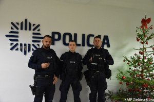 Trzech policjantów na tle Policji i choinki