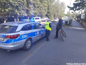 Policjantka ruchu drogowego obok radiowozu rozmawia z mężczyzną opierającym się o rower stojący na chodniku