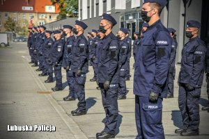 Szereg policjantów w granatowych mundurach z maseczkami na twarzach