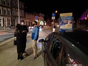 Umundurowany Policjant rozmawia z dwójką obywateli na chodniku