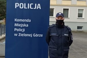 Umundurowany policjant stojący przed budynkiem KMP Zielona Góra