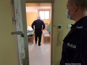 Łysy mężczyzna stojący w celi , obserwowany przez policjanta