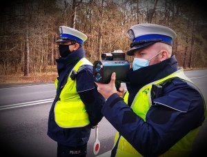 Dwóch Policjantów mierzy prędkość pojazdom na drodze