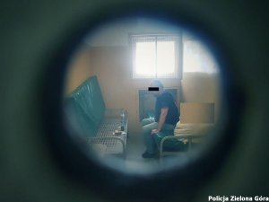 Mężczyzna siedzący w celi policyjnych pomieszczeń dla osób zatrzymanych