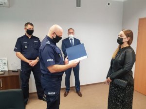 Trójka policjantów w trakcie dziękowania pracowniczkom poczty polskiej za obywatelską postawę.