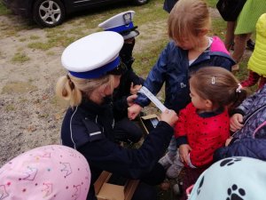 Policjantka zakłada odblaski dzieciom.