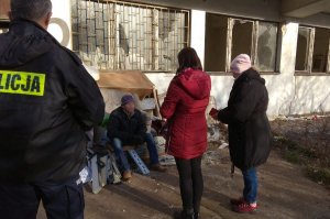 Policjant i dwóch pracowników zielonogórskiej noclegowni rozmawiają z bezdomnym