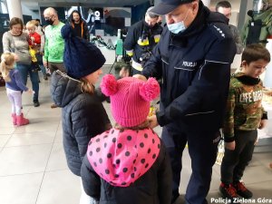 Policjant wręcza upominki dzieciom.