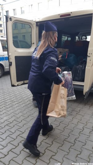 Policjantka niesie kolejne torby z ubraniami dla bezdomnych.