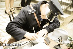 Policjant siedzi przy biurku i wypełnia dokumenty.