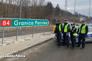 Czwórka policjantów stojąca przy znaku Granica Państwa.